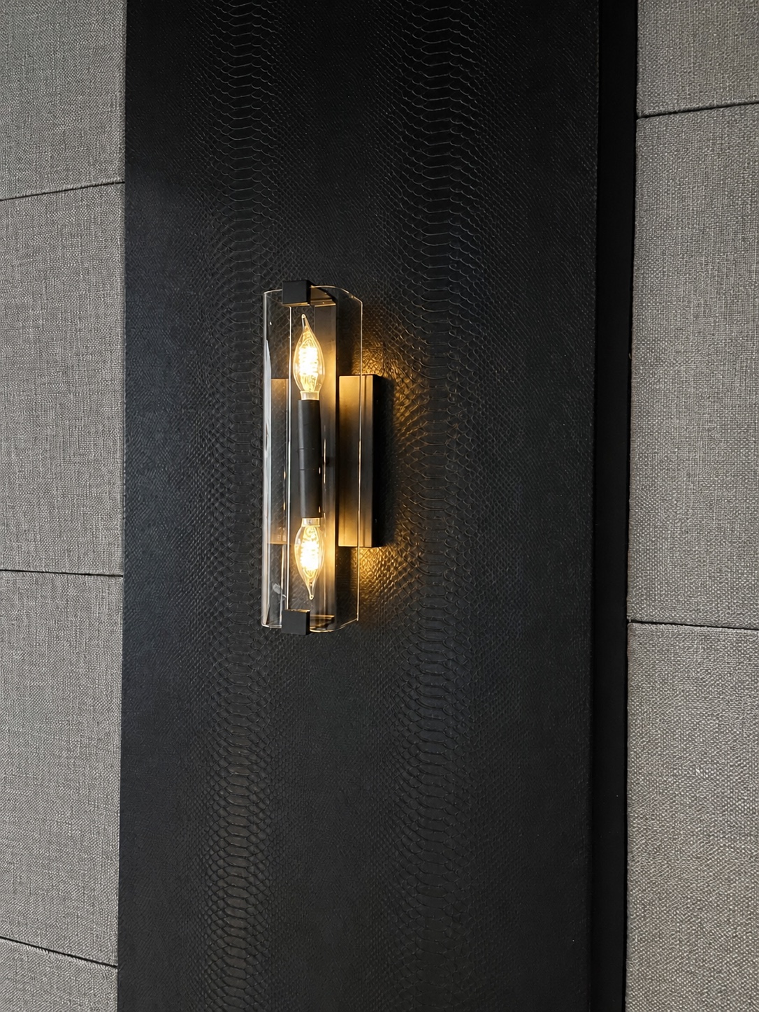 Warm glass sconce set into textured black wall finish