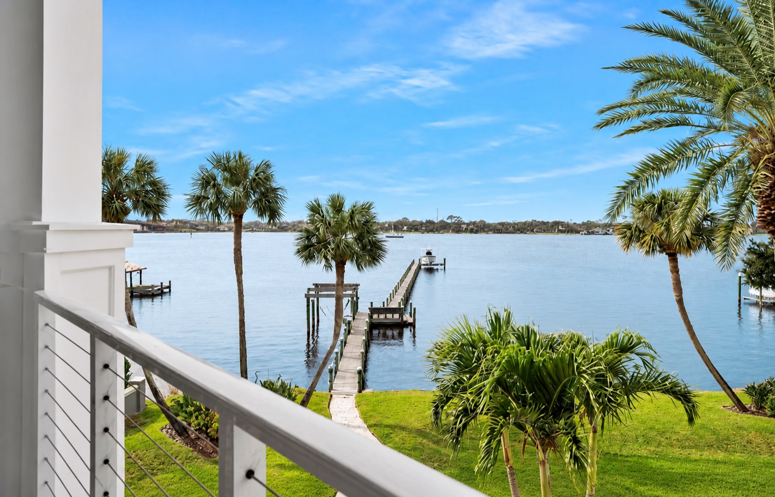 Palm-framed balcony view toward the private dock and water